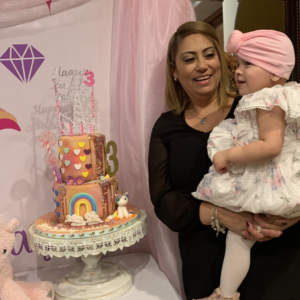 Isabella being held by a woman posing with her birthday cake