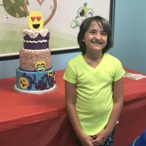 Kailyn standing next to an emoji cake