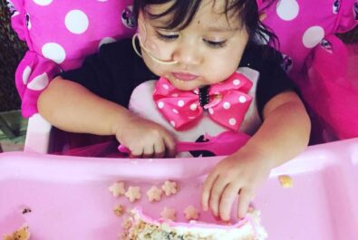 baby in a high chair eating a slice of cake