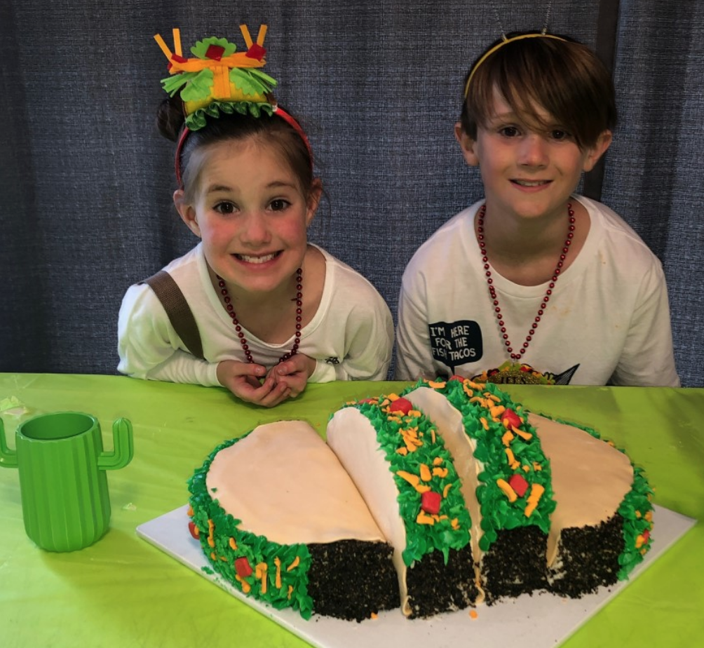 two kids next to a taco cake