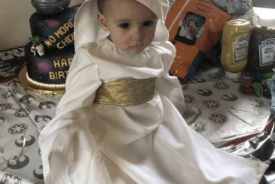 baby in a robe next to a star wars cake
