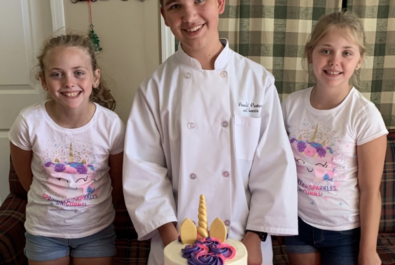 chef with two girls next to a unicorn cake