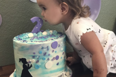 kid blowing the candle off a custom cake