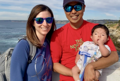 parents with a baby near the ocean