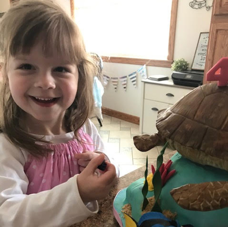 girl next to a turtle cake