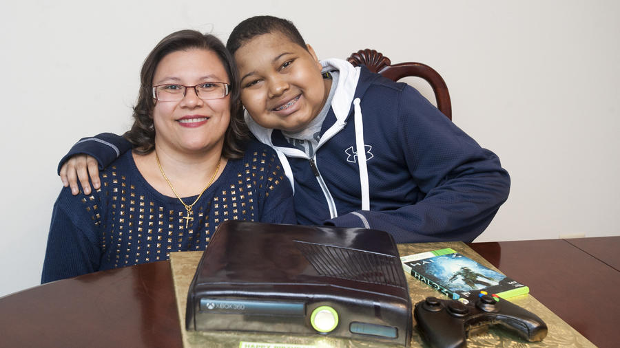 Christina Blunt smiles with her son Xavier Blunt after the nonprofit Icing Smiles worked with Crofton bakers Cakes 2-A-T o deliver a lifelike Xbox cake to him the day before his 13th birthday. Xavier recently received a liver transplant.