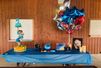 table with birthday cake, gifts, and balloons