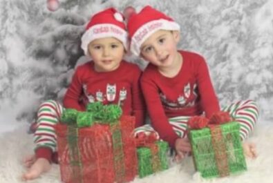 two kids dressed in christmas attire with presents